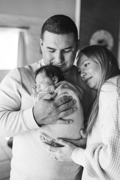 newborn baby girl posing with her parents during her newborn session