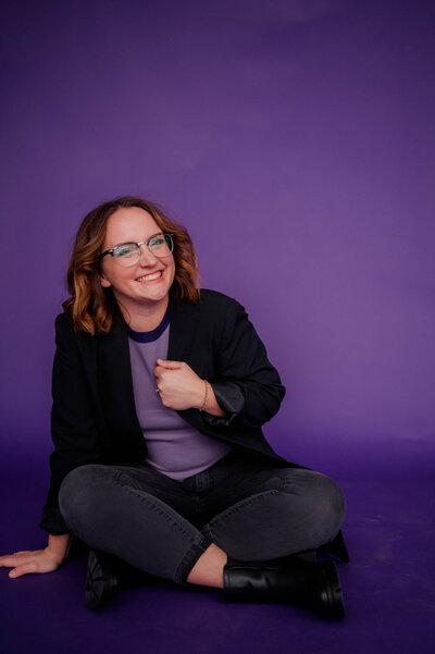 Rachel Hahn, owner of Rachel B Photography, poses in front of purple backdrop.