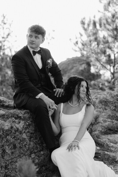 A bride and groom in an editorial sitting pose in the Black Hills.