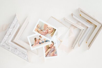 Photo prints of a lifestyle newborn session laying on top of a gold glass photo box.