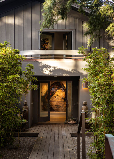 Interior design photography of a modern entrance with a wooden path and bamboo landscaping.