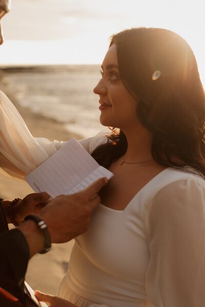 A bride reading her vows to her groom on the beach