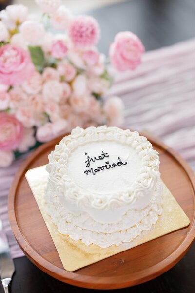 A small white cake with "just married" written in icing 