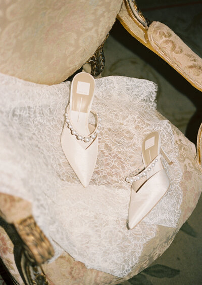 brides shoes laying on veil in a chair captured on film camera