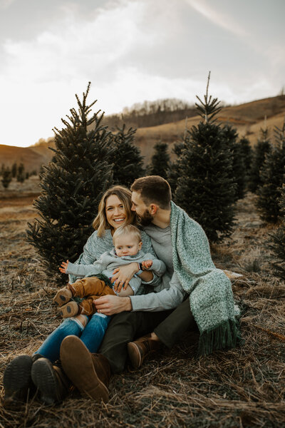 family sitting among christmas trees