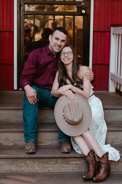 couple taking an engagement photo outside of a barn