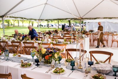 Wedding reception with bright florals under white tent