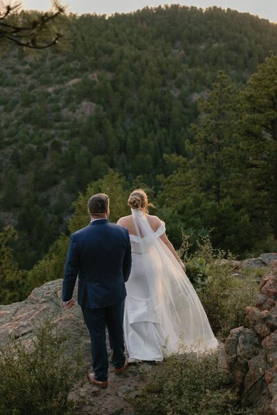 Bride and groom walk in forest after Colorado wedding ceremony.