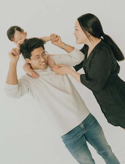 baby on dads shoulder while mom helps