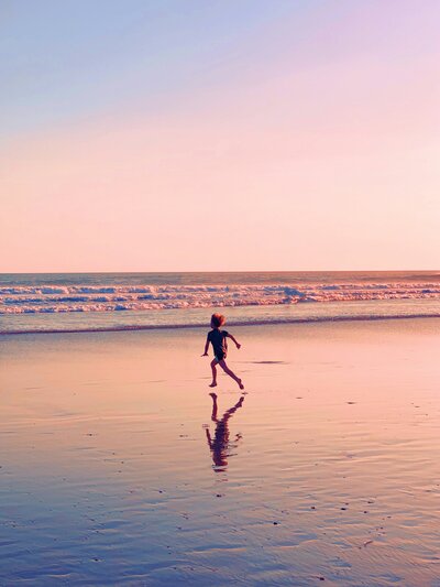 boy running on beach in sunset
