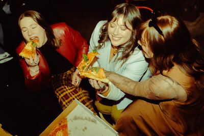 a group of women laughing and enjoying pizza together