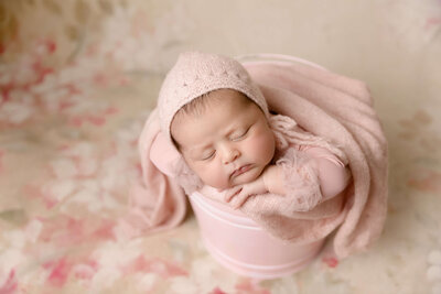 Baby girl posed in studio in pink bucket by Ashley Nicole