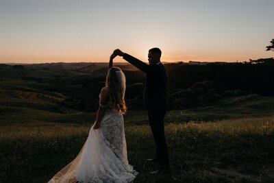 Bride and groom dancing in the sunset light overlooking Kumeu Valley Estate