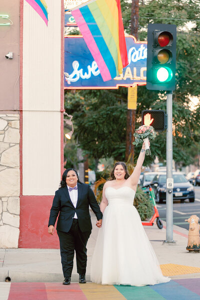 Lesbian couple celebrating their marriage in front of rainbow crosswalk in Long Beach California