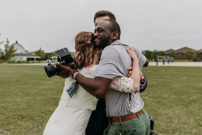 photographer embracing bridal couple