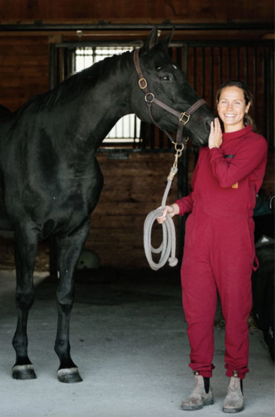 a girl standing next to her black horse