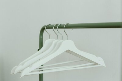 Image of 4 white clothes hangers on a green rack