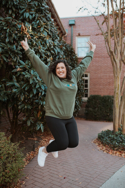 Cassie jumping in the air with her arms up