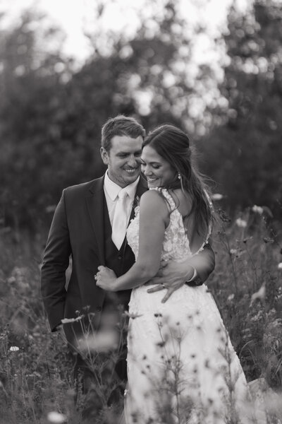 man and woman embracing while standing in a field of flowers