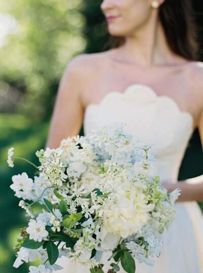 Fine art portrait of a bride with a blue and white bouquet at a coastal New England wedding, blending timeless and organic style.