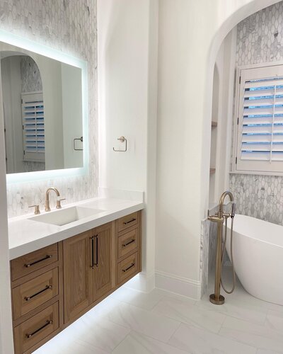 An elegant bathroom designed by top interior designers near Frisco, featuring gold decorations and white materials for a luxurious look.