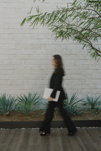 Blurred image of a wedding planner walking and holding a laptop 