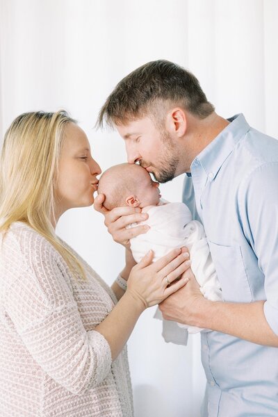 Newborn being kissed by mom and dad