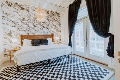 bedroom with marbled wallpaper, checkered rug, blue pillows and curtains
