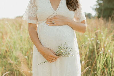 Expecting mother holding flowers over baby bump.
