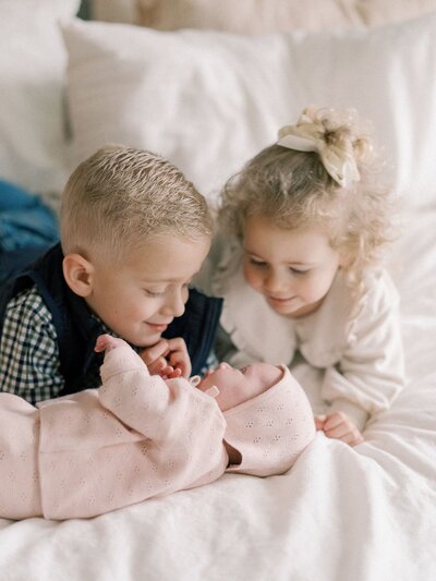 Siblings looking at newborn sibling during newborn session