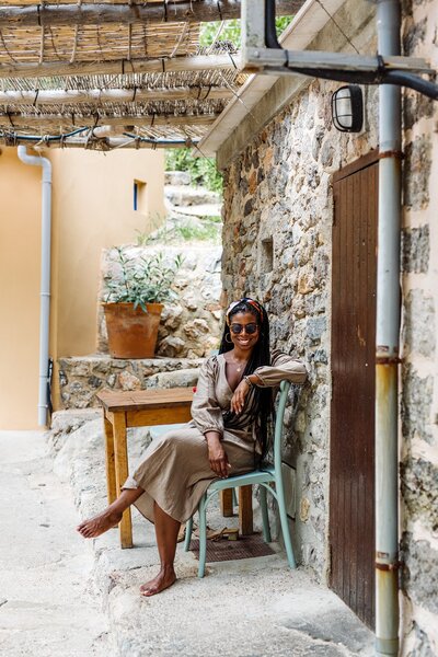 Fallon Carter - Honeymoon, Group, and Solo Travel Planner sits outside a stone building at a table in Mallorca, Spain