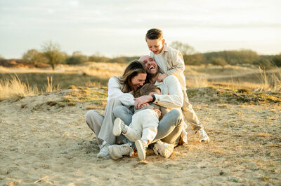 Familiesessie in Leiden van een gezin in de duinen tijdens zonsondergang. 