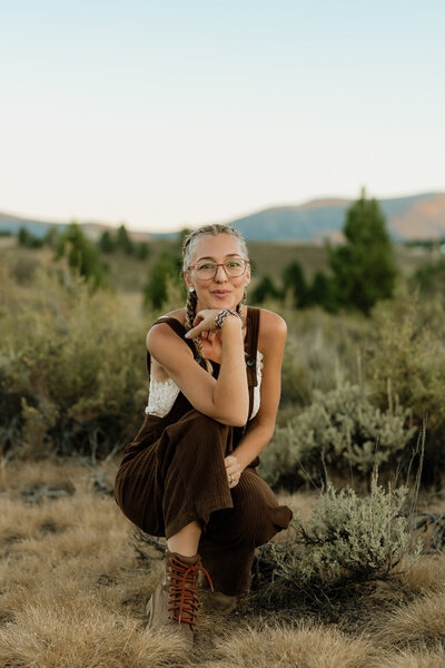 Christina Landini in a white dress looking back at the camera with mountains in the background