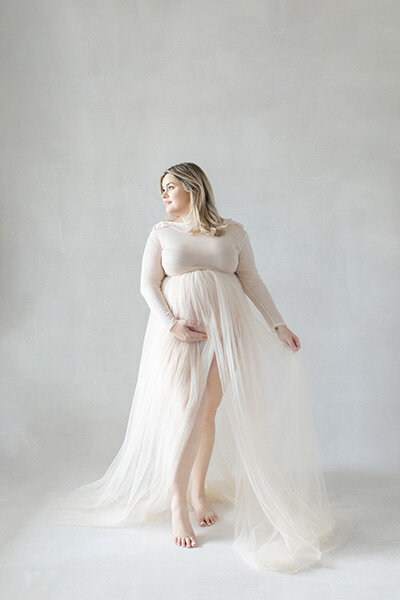 Elegant maternity portrait of Tampa mom-to-be in soft cream tulle gown bathed in natural light