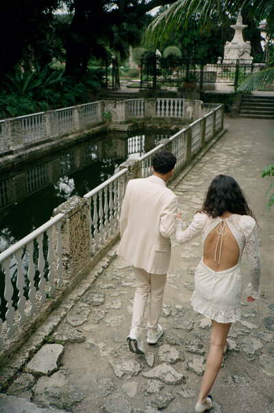 bride and groom walking and holding hands by top destination wedding photographer