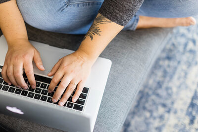 Sitting cross legged, typing on Macbook