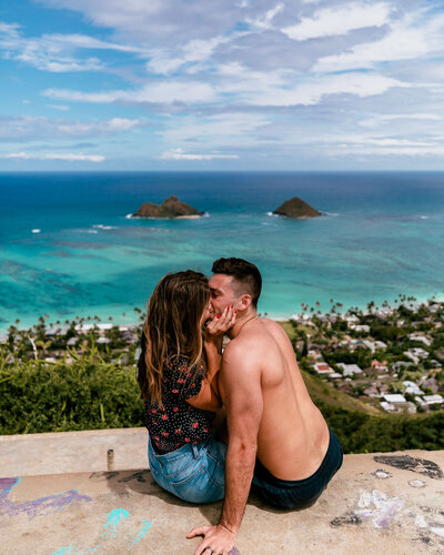 man and woman kissing in front of ocean view