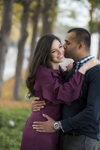 A person kissing their partner's cheek as they have their arms around each other 