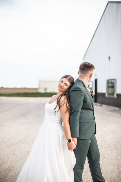 A couple in their wedding attire leaning on each other under a Iowa Sunset.