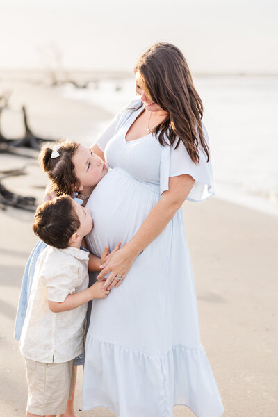 kids snuggling pregnant mom at the beach