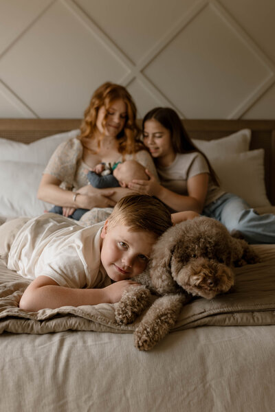 Mom and children together on the bed with their dog
