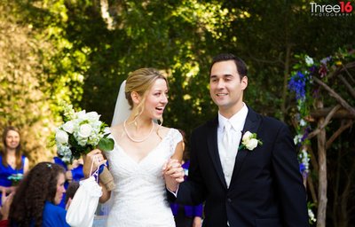 Bride and Groom smile as they walk down the aisle together