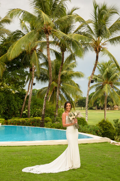 bride poses next to pool