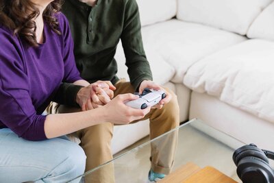Portrait of Alicia and spouse playing a video game together and headphones on the table