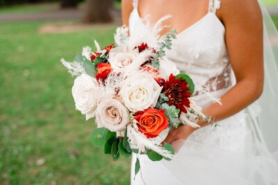 Detail photo of wedding bouquet a bride is holding with blush and orange roses
