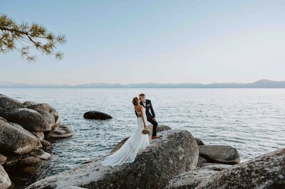 Bride and groom walking along a river within the mountains after their elopmenet