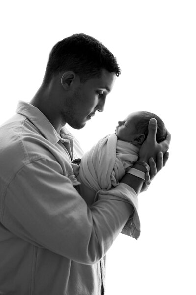 Black and white image of mom and dad holding newborn