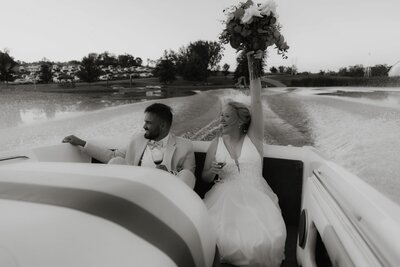 Bride and Groom do their grand exit on a boat, waving at their guests as they leave.