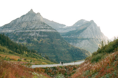 bride and groom running on a scenic road in glacier national park