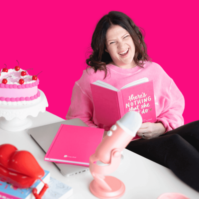 Emily, a brand and web designer, sits at her desk in a pink sweatshirt, speaking into a microphone.